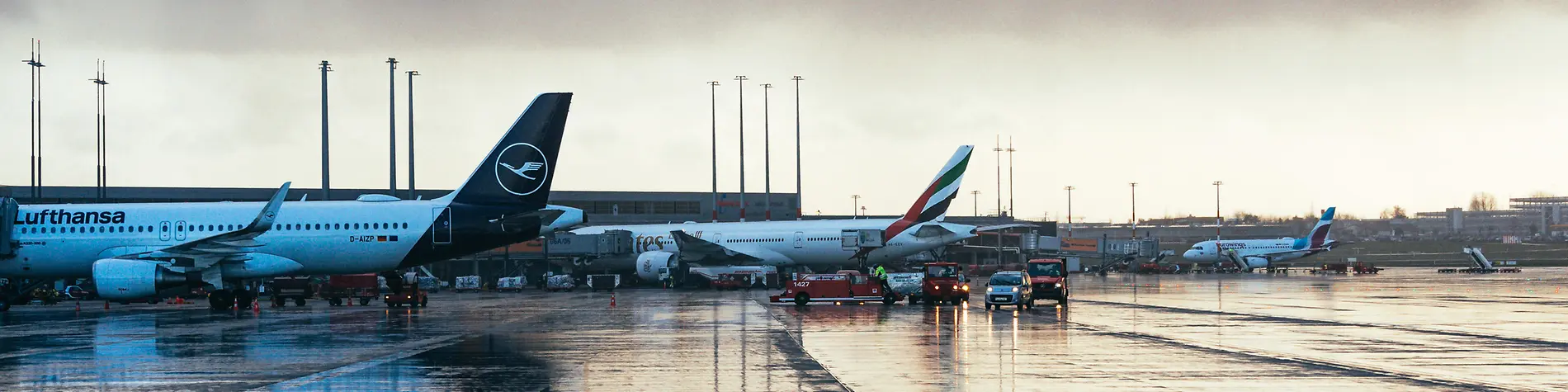 Flugzeuge stehen auf einem Flughafen. Auch Autos sind zu sehen.
